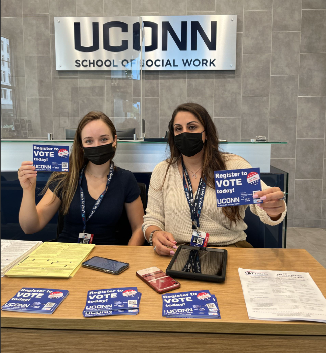 Two women wearing face masks and holding up signs