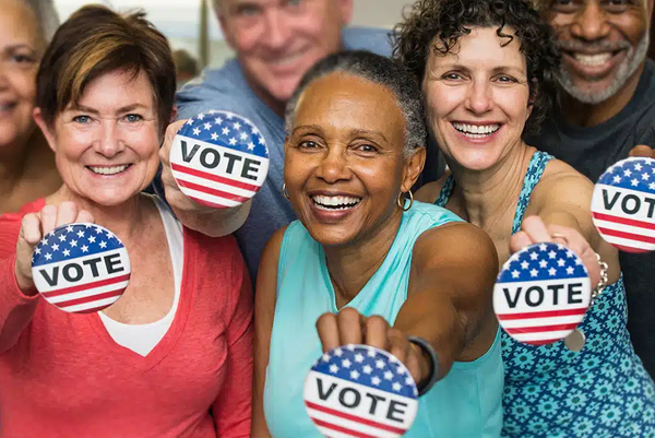 a group of seniors holding voting buttons for the camera