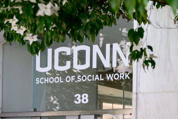 glass door with the logo and lettering of UConn School of Social Work with plants and flowers above 